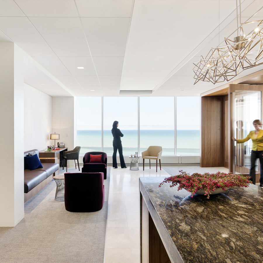 a room with a marble counter and chairs and a person standing by the ocean